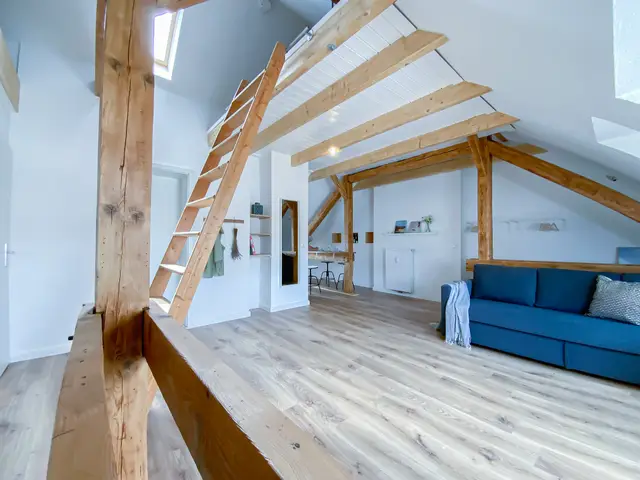 Offener Wohnraum mit Holzleiter und blauem Sofa, Über den Dächern